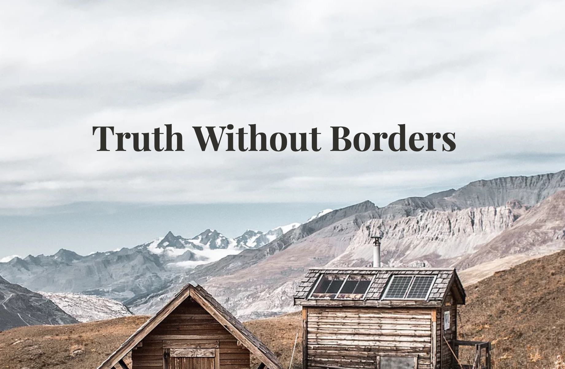 Cabins against mountains with 'Truth without Borders' overhanging it