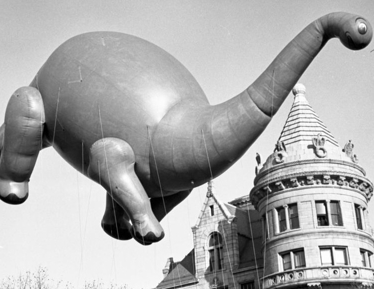 Sinclair's dinosaur balloon Dino the Dinosaur, parade balloon, floating past the AMNH turret, November 1969, Photographer Florence Stone.