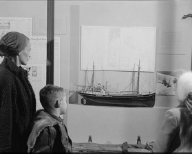 Photograph of a woman and children viewing the Lincoln Ellsworth Exhibit, at the AMNH in January, 1957